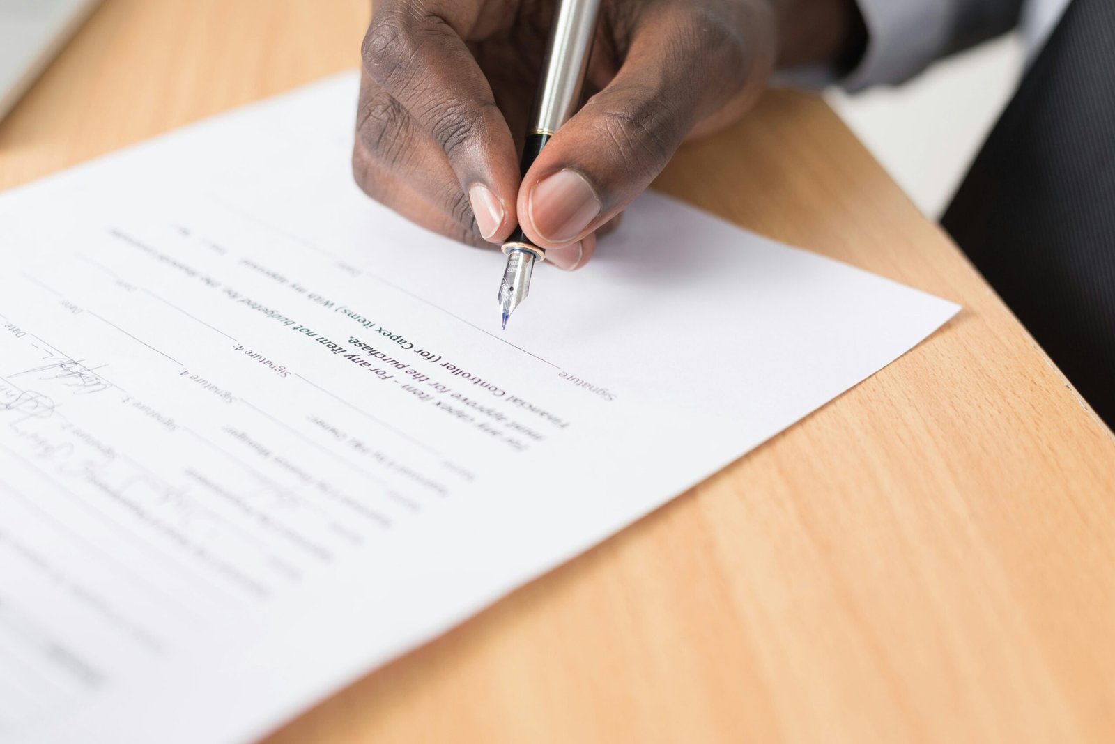 Persona revisa y firma un documento sobre una mesa; fotografía de referencia, no corresponde a la elección de la JEP.